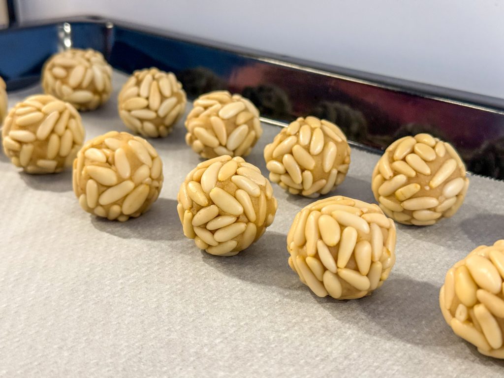 Panellets de pinyons sobre paper de forn, preparats per coure